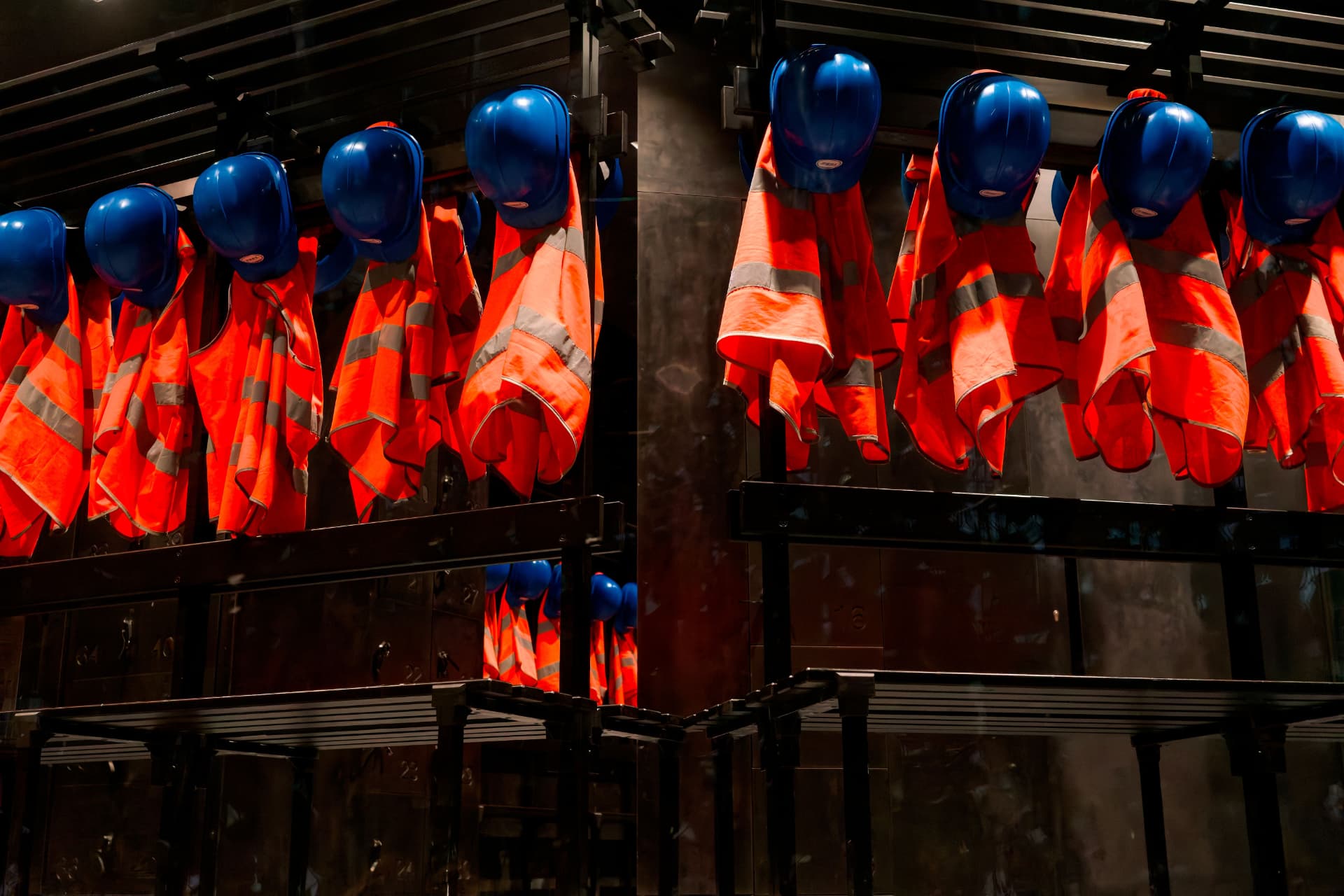 Hi-vis vests and blue hard hats hanging in a site welfare cabin